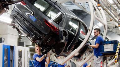 Mitarbeiter arbeiten am neuen Volkswagen Golf 8 an einer Produktionslinie in einem VW Werk.