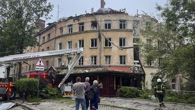 Menschen beobachten einen Feuerwehreinsatz nach einem Raketenangriff in Lwiw, Ukraine