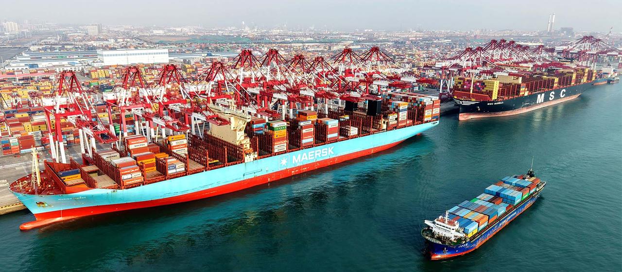 Voll beladene Containerschiffe im Hafen von Qingdao, China.