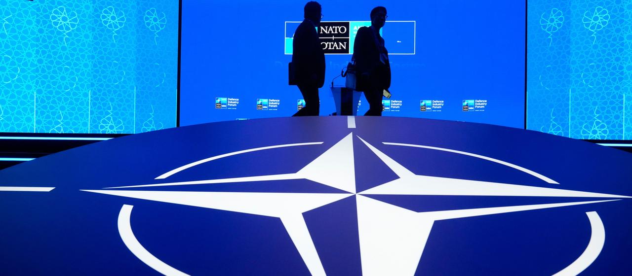 Zwei Männer laufen an einem NATO-Logo in Ankara vorbei