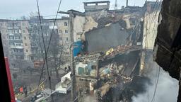 Ein von einem Angriff zerstörtes Haus, davor Einsatzwagen