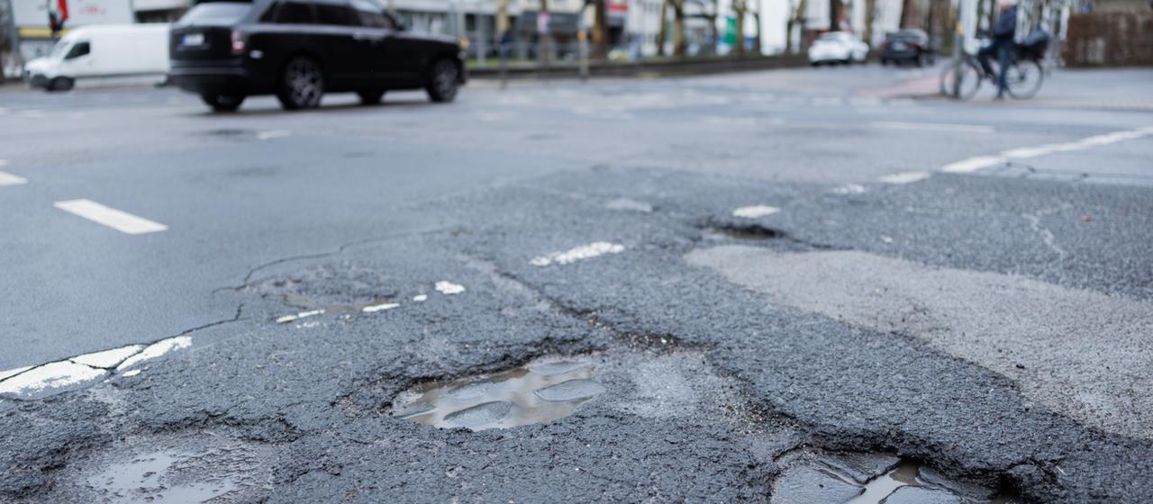 Autos fahren auf einer Straße mit Schlaglöchern.