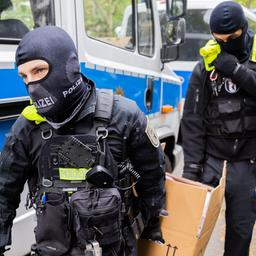 Polizisten tragen bei einer Hausdurchsuchung in Berlin-Kreuzberg einen Karton zu einem Fahrzeug. 