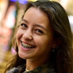 Ein Mädchen, dass eine feste Zahnspange trägt und lächelt.