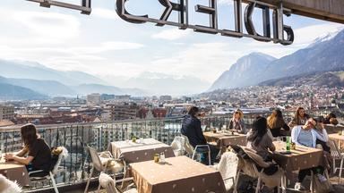 Aussicht vom ADLERS-Hotel auf die Stadt Innsbruck mit ihren Häusern, Dächern und Bergen.