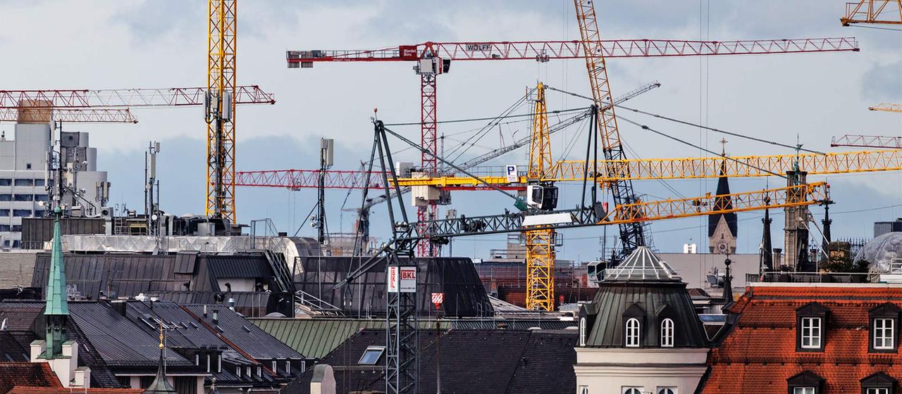 Zahlreiche Baukräne auf Baustellen in München.