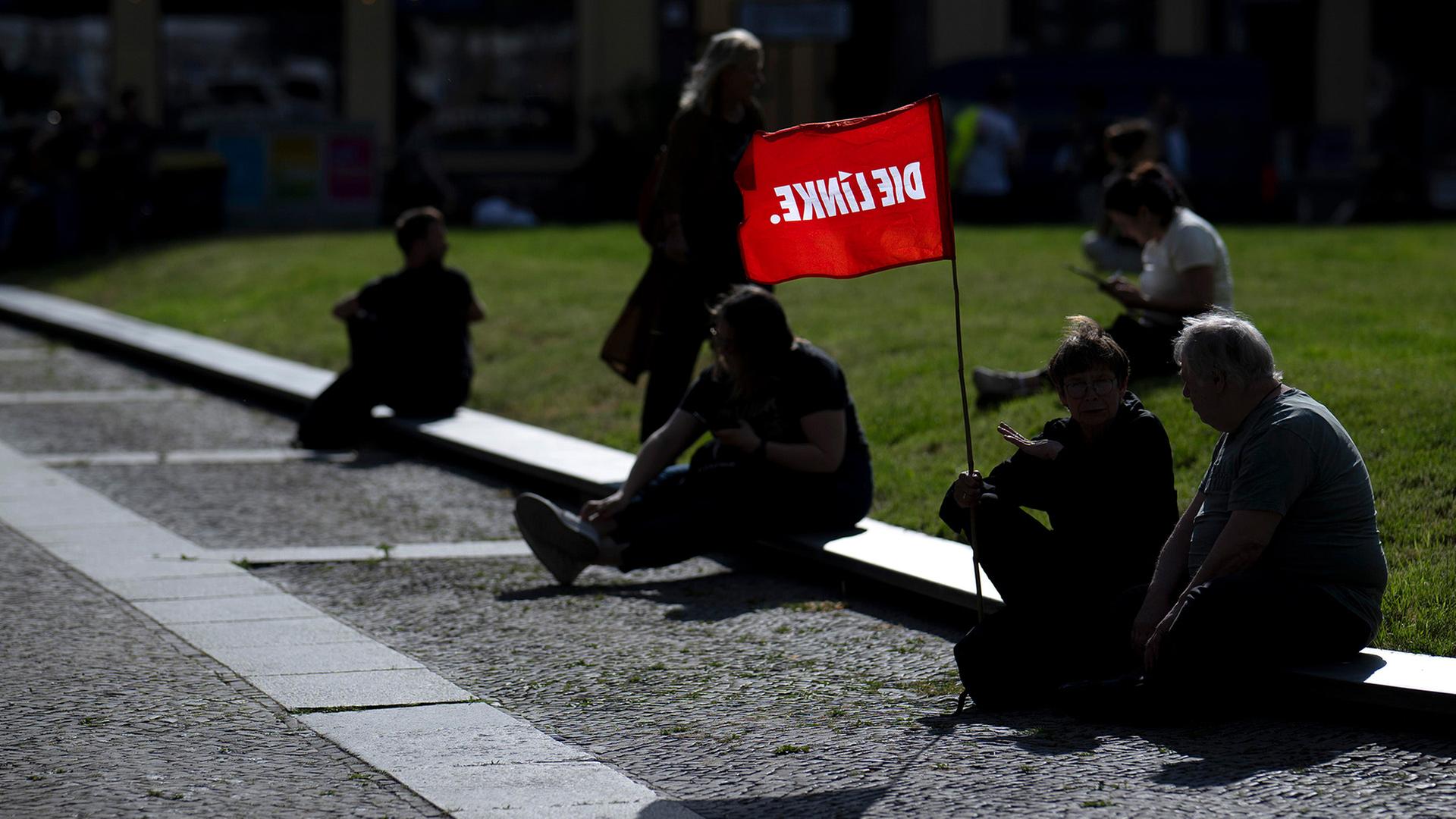 Demonstranten sitzen mit einer Fahne der Partei 