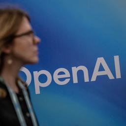 Eine Person geht an einem OpenAI-Logo vorbei.
