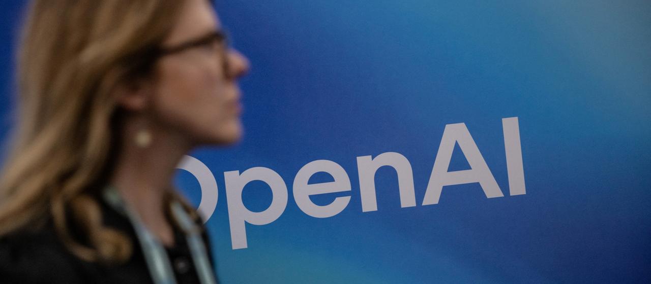 Eine Person geht an einem OpenAI-Logo vorbei.