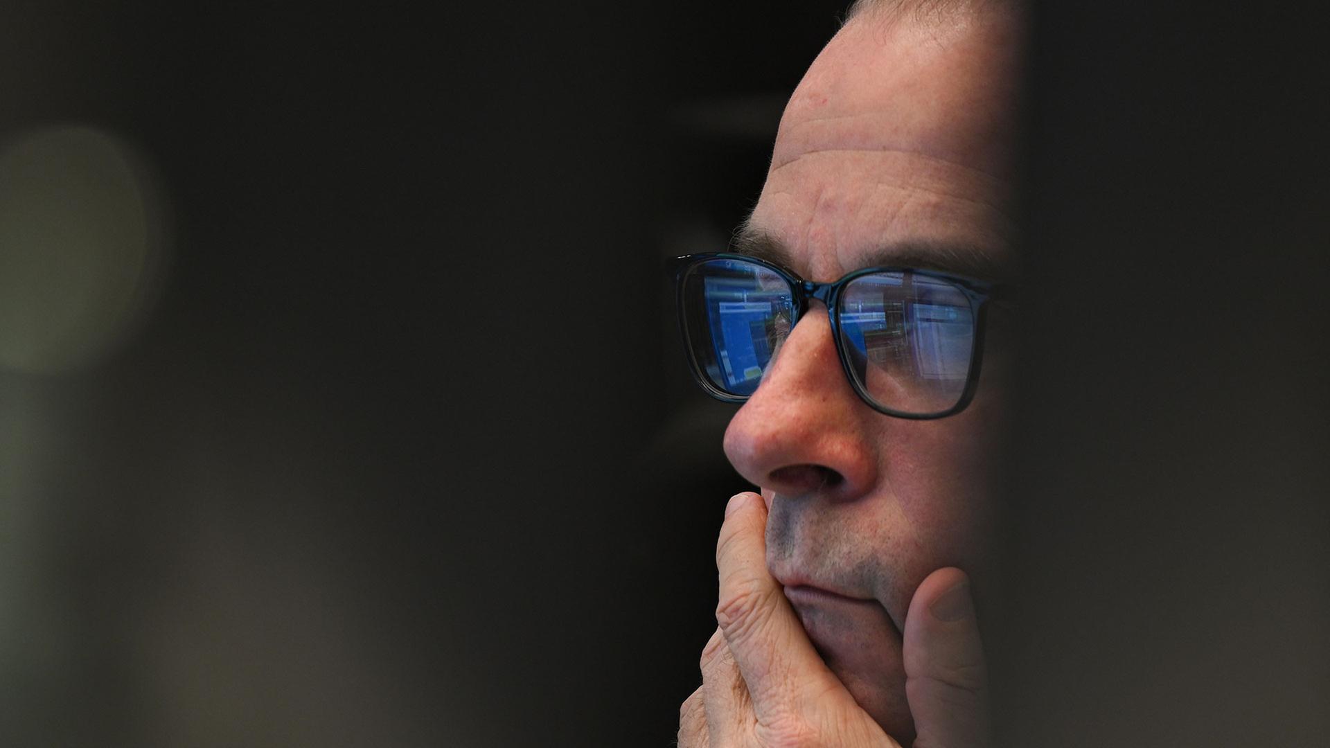 Ein Aktienhändler sitzt auf dem Parkett der Wertpapierbörse vor seinen Monitoren. | picture alliance/dpa