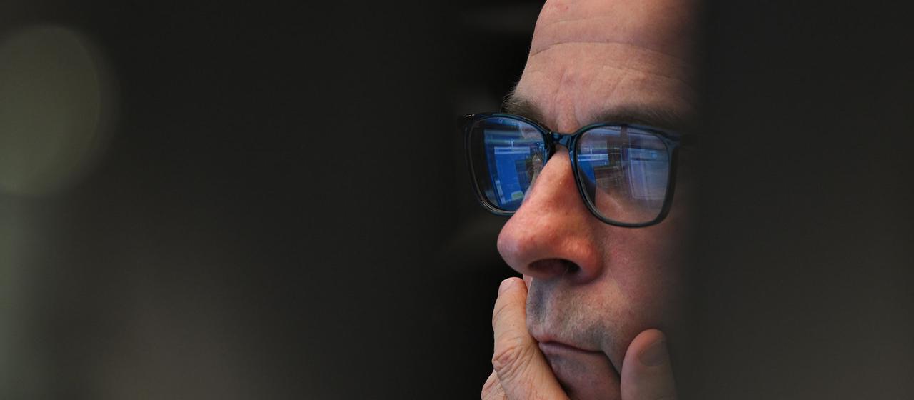 Ein Aktienhändler sitzt auf dem Parkett der Wertpapierbörse vor seinen Monitoren.