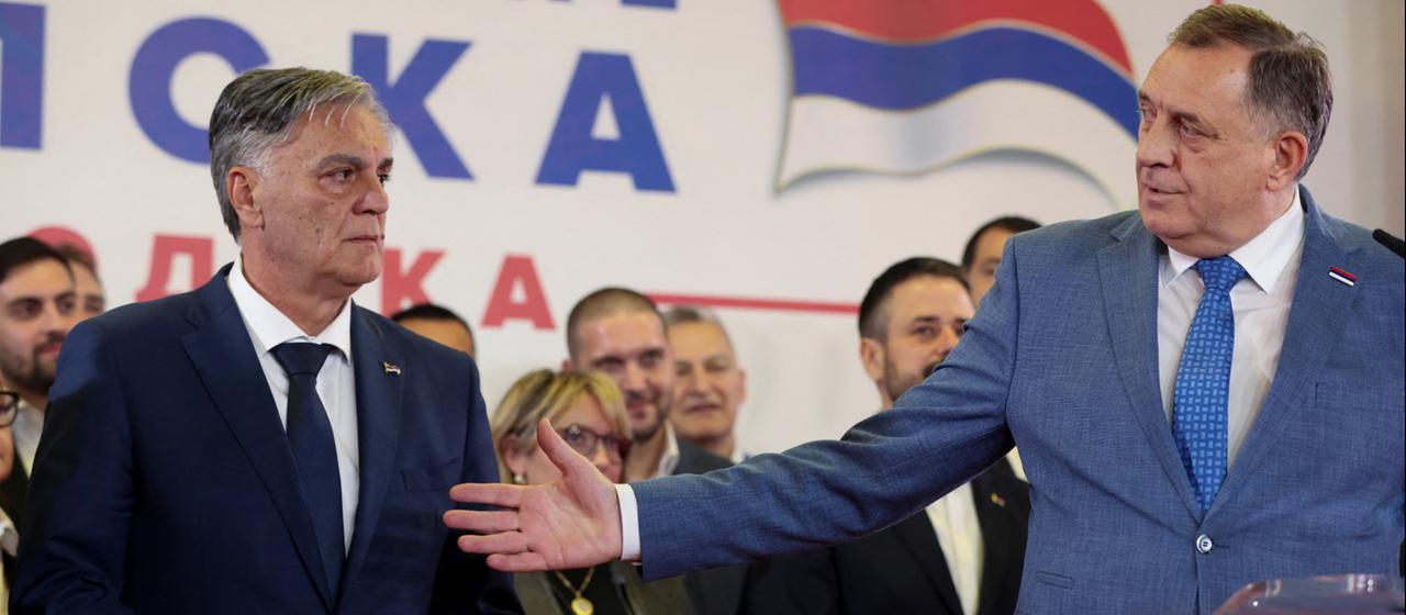 Milorad Dodik zeigt mit einer Handbewegung auf  Sinisa Karan.