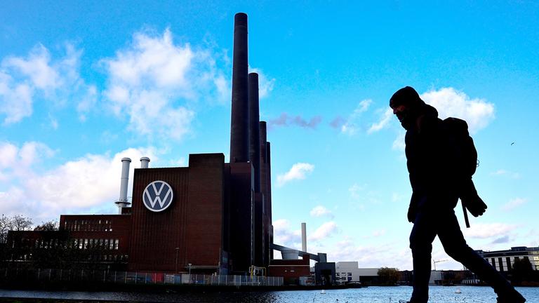 Eine Person geht am Volkswagenwerk in Wolfsburg entlang.