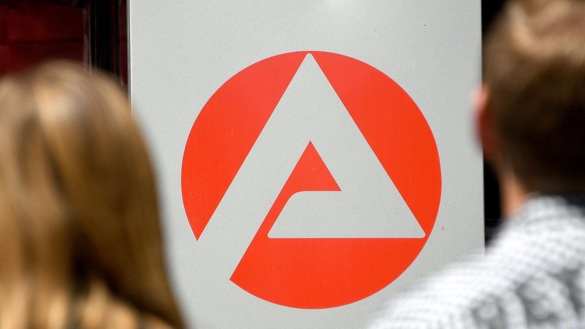 Zwei Personen stehen vor dem Logo der Agentur für Arbeit | picture alliance/dpa | Carsten Rehder