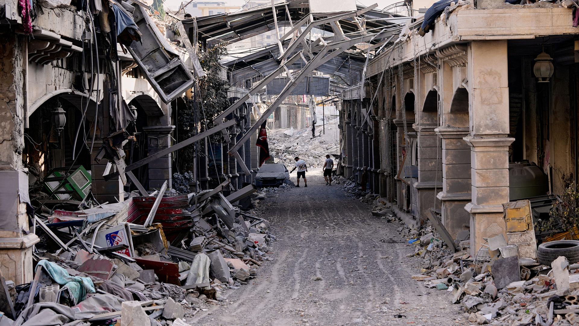 Menschen befinden sich in den Trümmern zerstörter Gebäude. | AP Photo/Hussein Malla