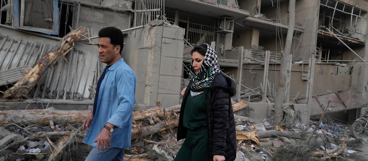 Menschen gehen an Gebäuden vorbei, die bei einem Angriff auf eine Polizeistation während der laufenden gemeinsamen US-amerikanisch-israelischen Militärangriffe in Teheran beschädigt wurden.