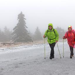 Wanderer sind bei Schneefall auf dem Brocken unterwegs.