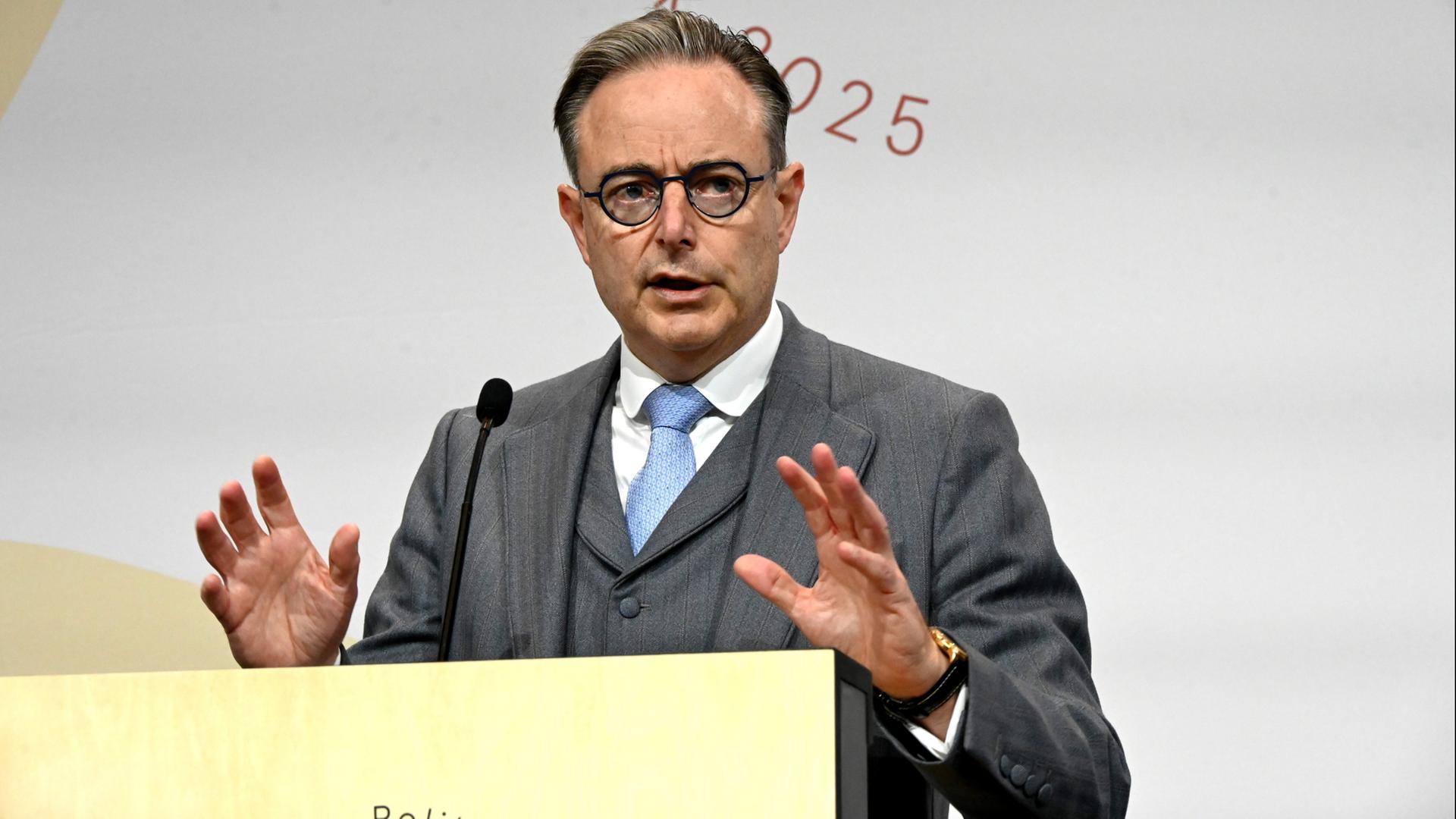 Belgiens Regierungschef Bart de Wever hebt während einer Rede beide Hände. | dpa