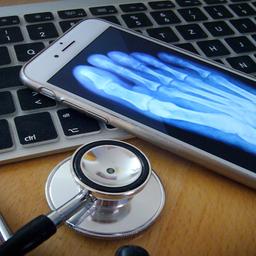 Ein Stethoskop liegt neben einem Handy und einer Tastatur.