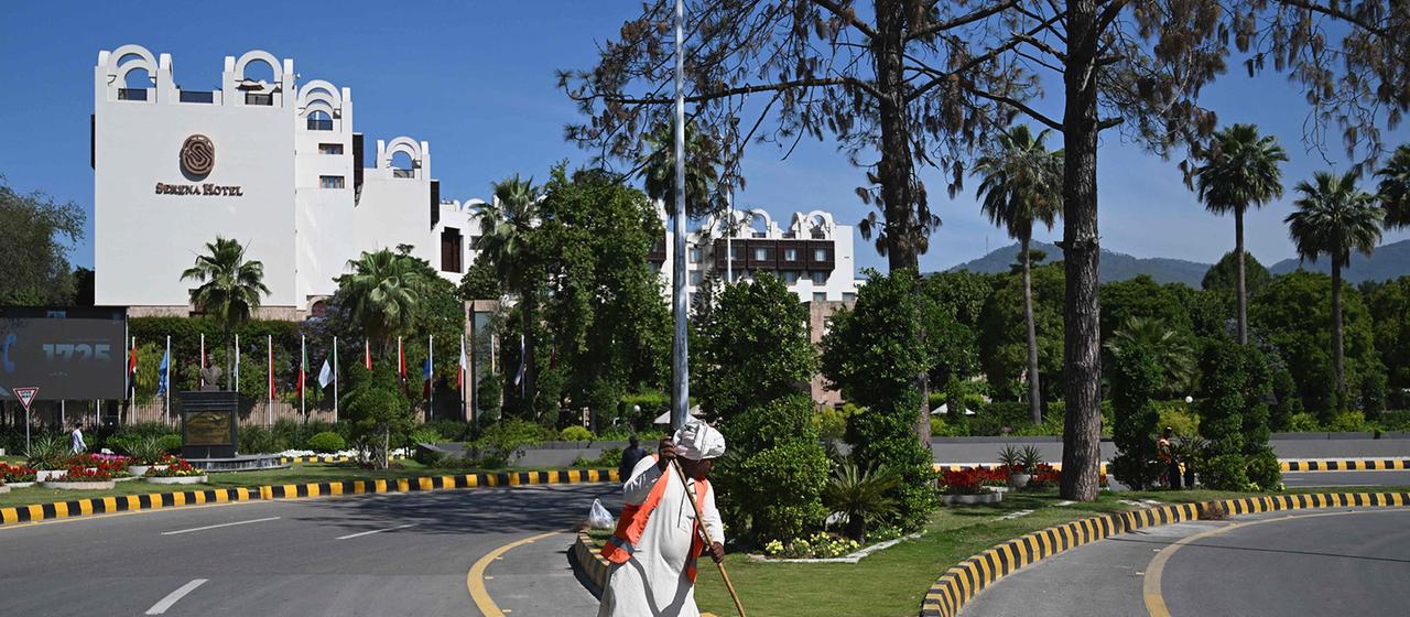 A street cleaner sweeps a street in front of the Serena Hotel.