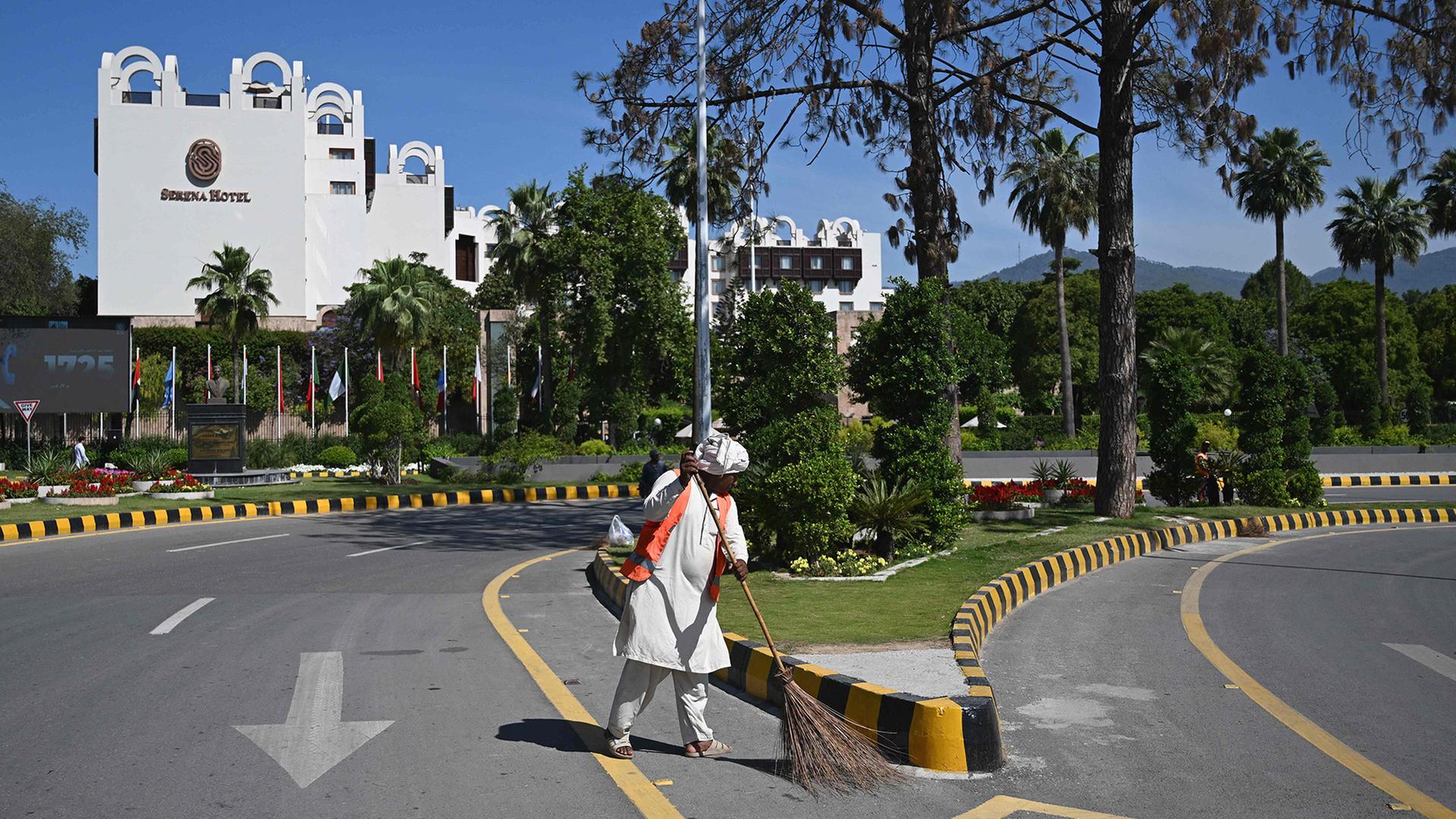 Ein StraÃenreiniger kehrt eine StraÃe vor dem Serena Hotel. | AFP