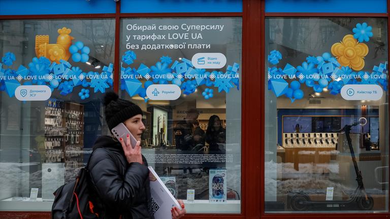 Eine Frau geht an einem Geschäft des ukrainischen Telekommunikationsunternehmens Kyivstar vorbei.