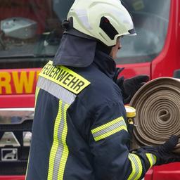 Ein Feuerwehrmann wickelt einen Schlauch auf.