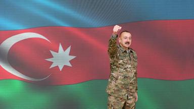 Aserbaidschans Präsident Ilham Alijew vor der Flagge des Landes