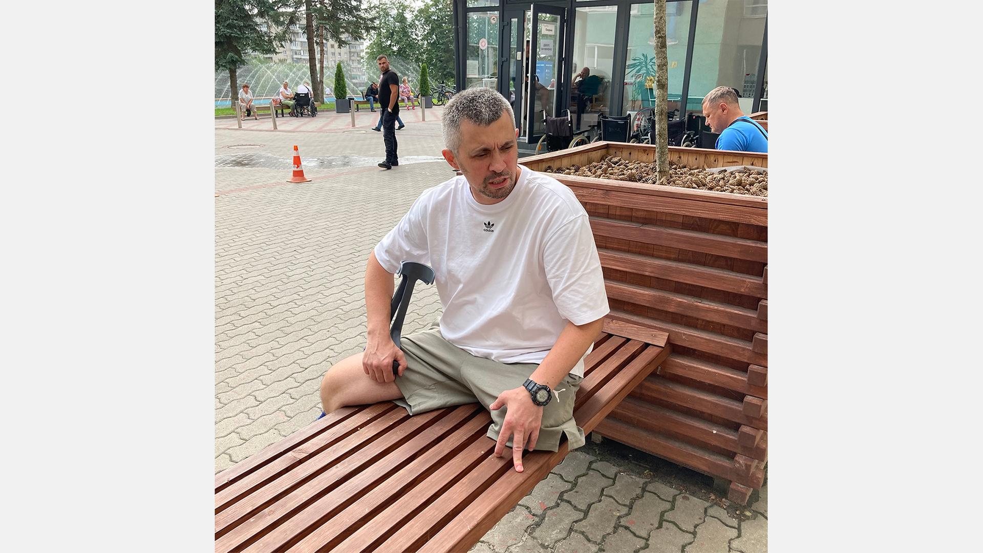Der ukranische Versehrte Michailo sitzt auf einer Bank vorm Krankenhaus.