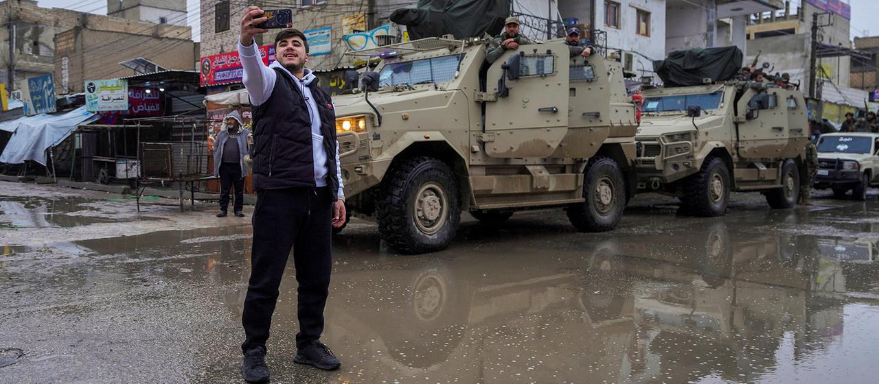 Ein Mann macht ein Selfie vor Fahrzeugen der syrischen Armee in Tabka.