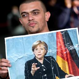 Flüchtling hält Bild von Angela Merkel