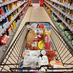 Einkaufswagen wird durch einen Supermarktgang geschoben.