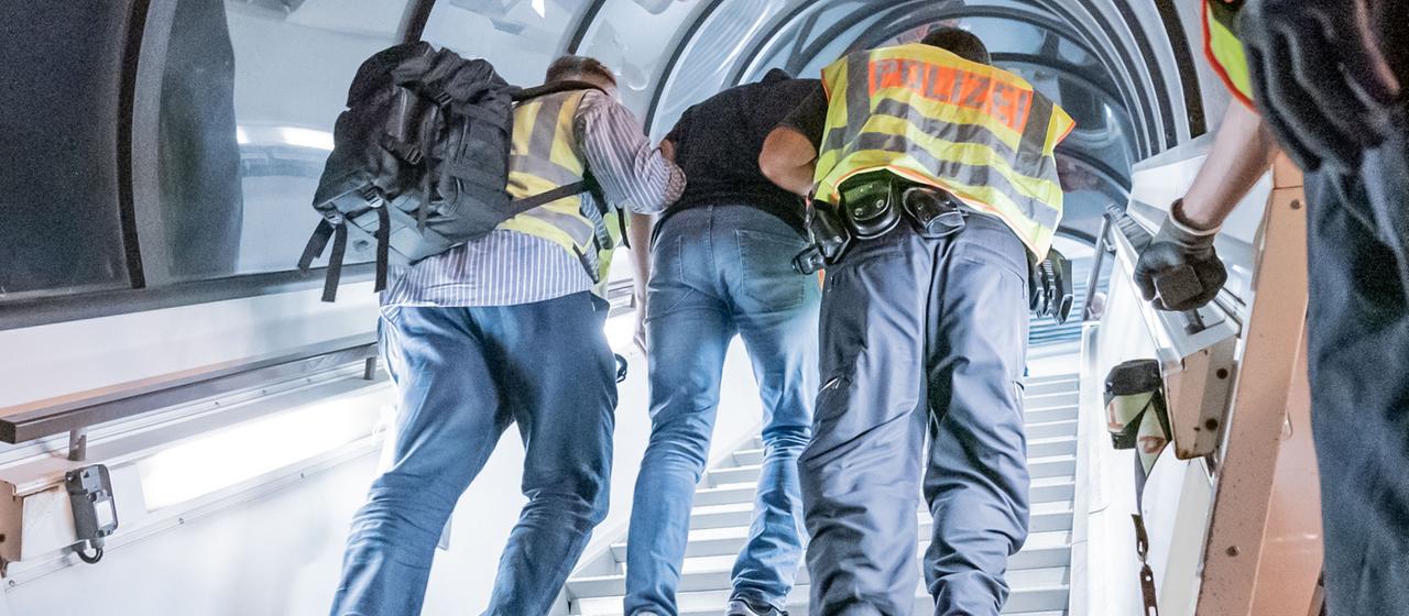 Polizeibeamte bringen einen Afghanen auf dem Flughafen Leipzig-Halle in ein Charterflugzeug.