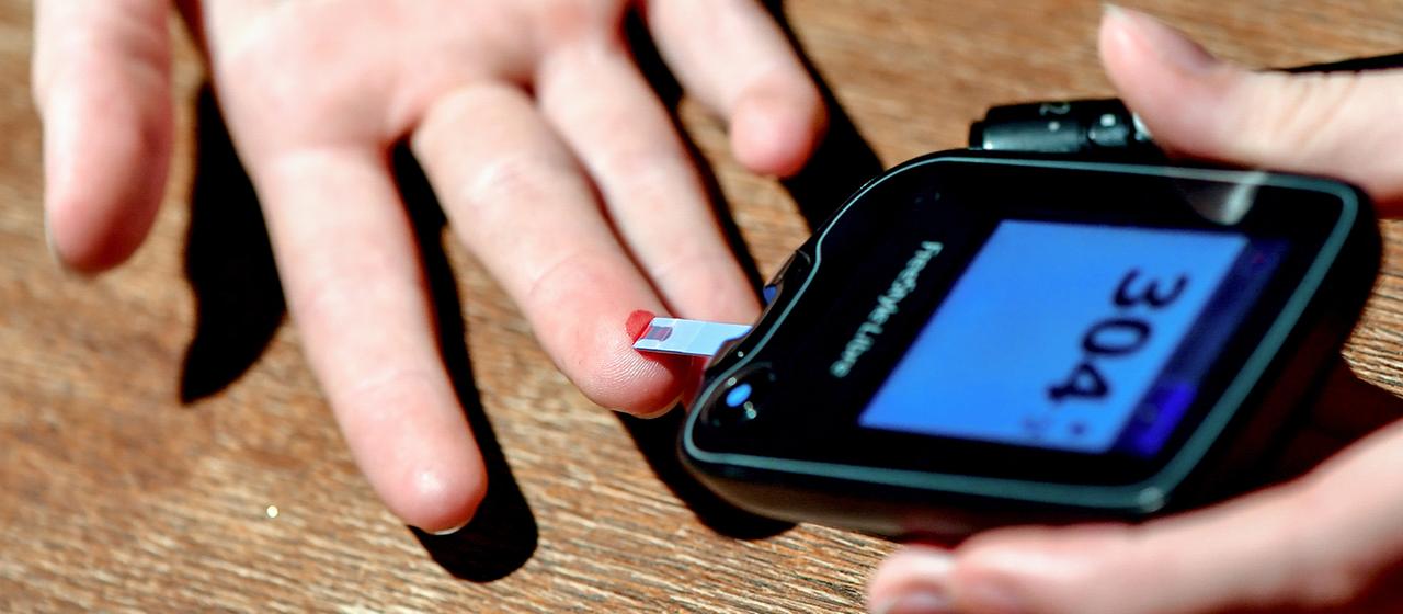 Der Blutzucker wird mithilfe eines Messgeräts gemessen.