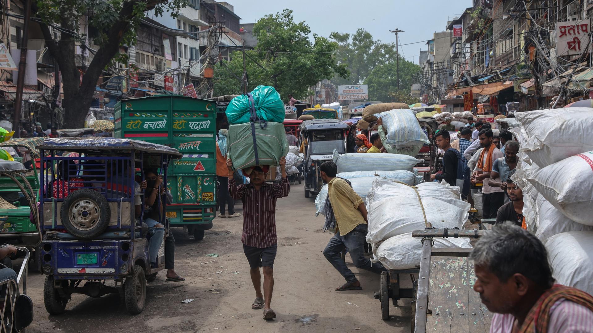 Ein Mann trägt Pakete auf seinem Kopf, während er über einen belebten Markt geht. | EPA