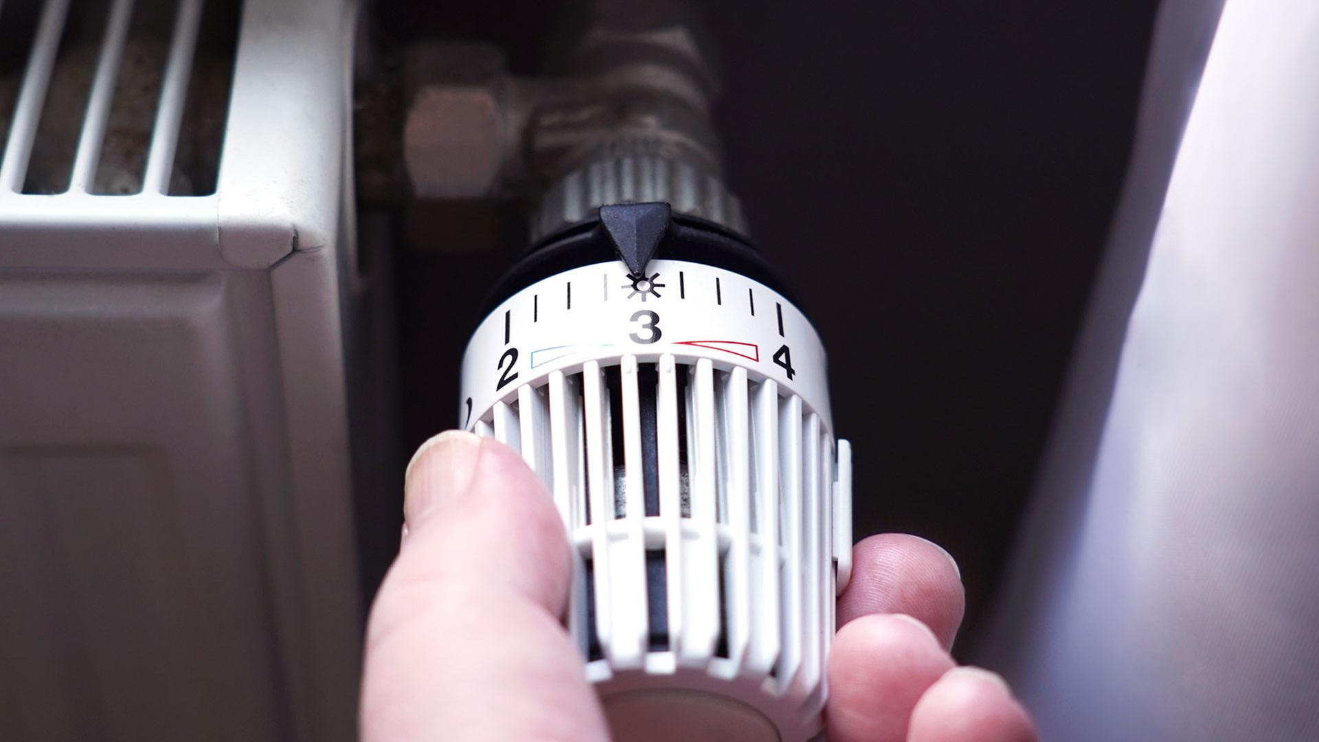 Nahaufnahme einer Hand, die ein Thermostat dreht | AdobeStock