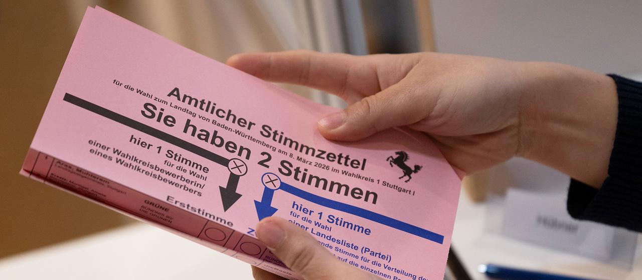 An election worker shows a postal voter a ballot paper for the 2026 Baden-Württemberg state election in the town hall.
