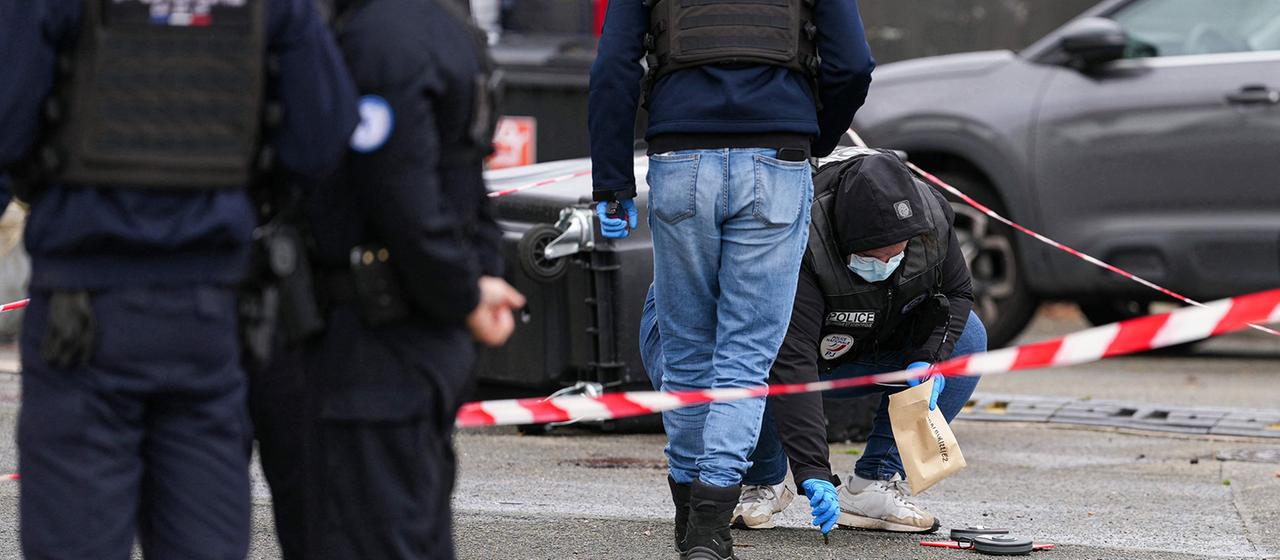 Kriminaltechniker sichern hinter einem Absperrband Spuren auf einer Straße.