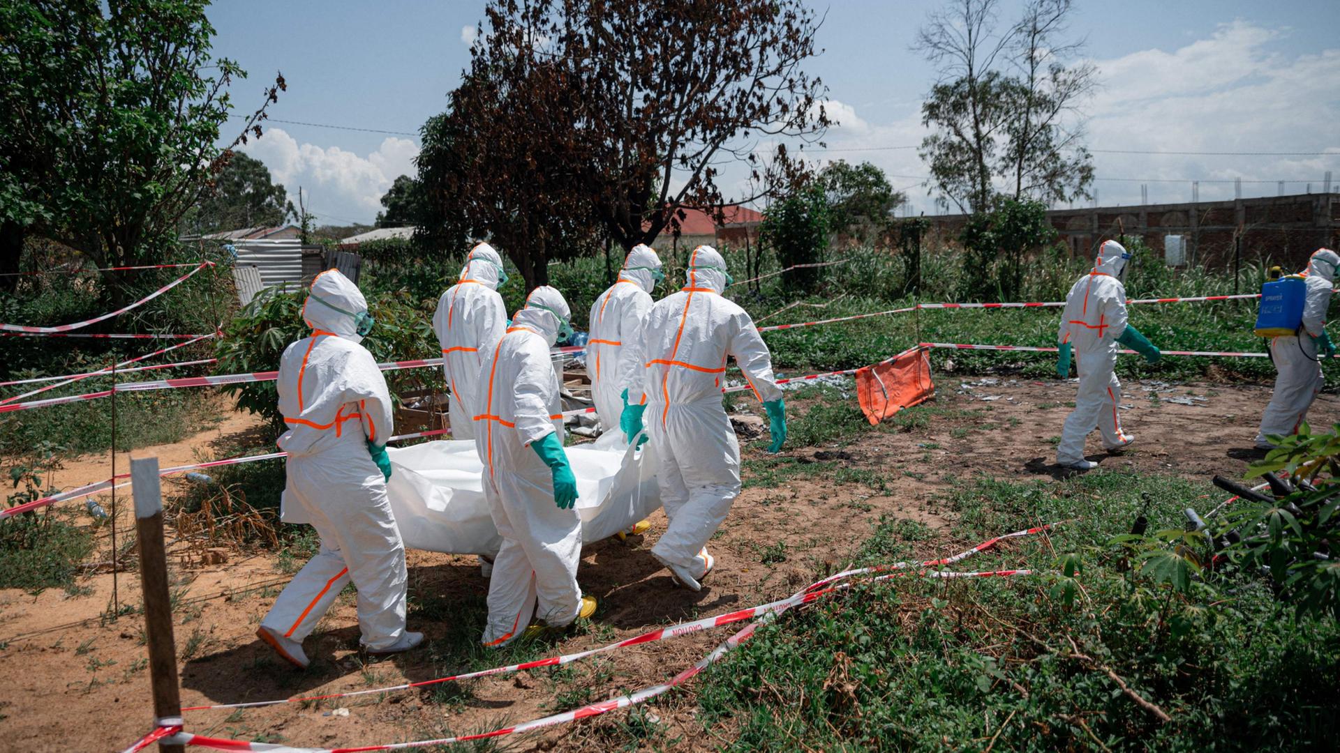 Freiwillige des Roten Kreuzes der Demokratischen Republik Kongo tragen in Schutzausrüstung die Leiche eines Ebola-Opfers aus der Leichenhalle des Gesundheitszentrums Rwampara in der Provinz Ituri. | AFP