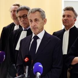 Nicolas Sarkozy steht mit seinen Anwälten und seiner Frau vor Mikrofonen im Gerichtsgebäude.