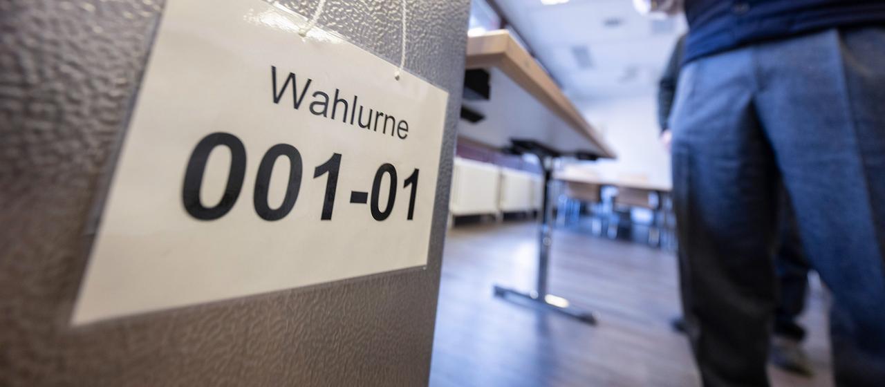Eine Wahlurne mit der Beschriftung "Wahlurne 001-01" steht in einem Wahllokal.