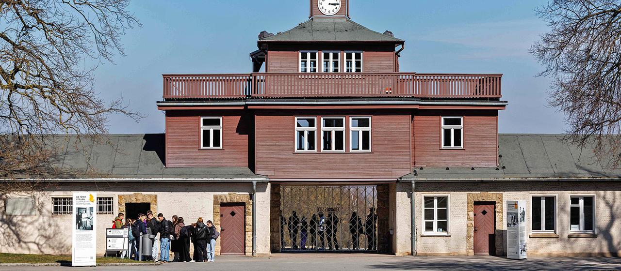 Besucher stehen am Haupttor der Gedenkstätte des ehemaligen Konzentrationslagers Buchenwald.