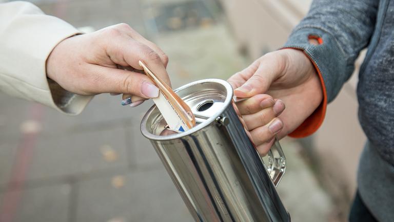 Geld wird in einen Spendendose gesteckt.