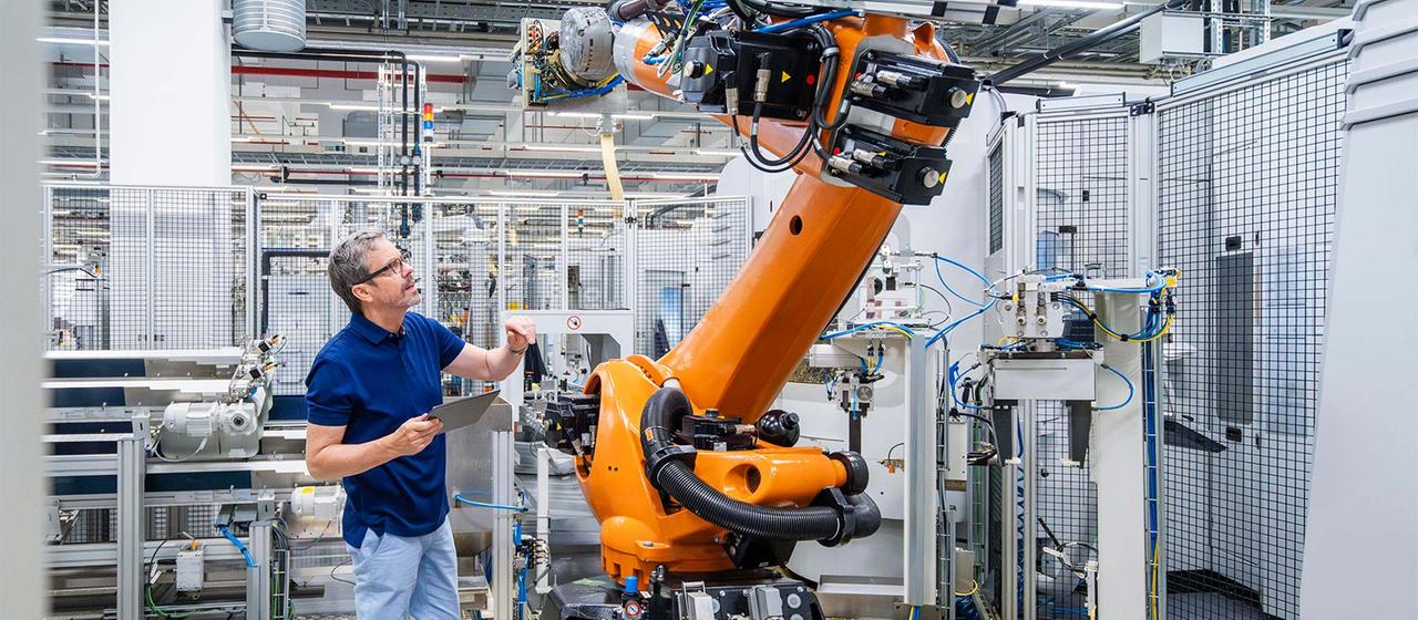 Mitarbeiter wartet einen Roboterarm.