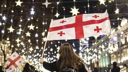 Eine Demonstrantin mit Georgien-Flagge vor Weihnachtsbeleuchtung auf dem Rustaweli-Boulevard in Tiflis
