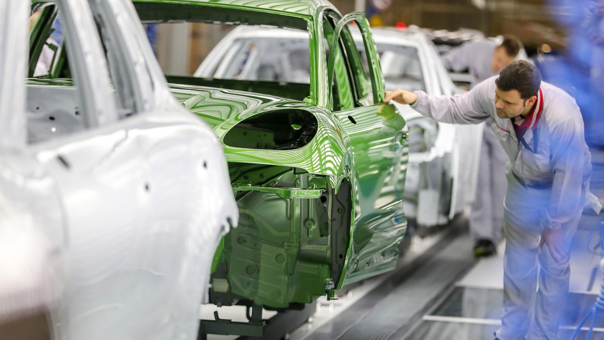 Ein Mitarbeiter prüft den Lack einer Karosse. | picture alliance/dpa