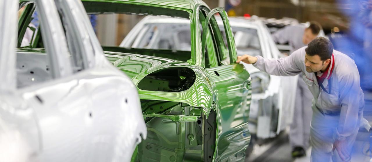 Ein Mitarbeiter prüft den Lack einer Karosse.