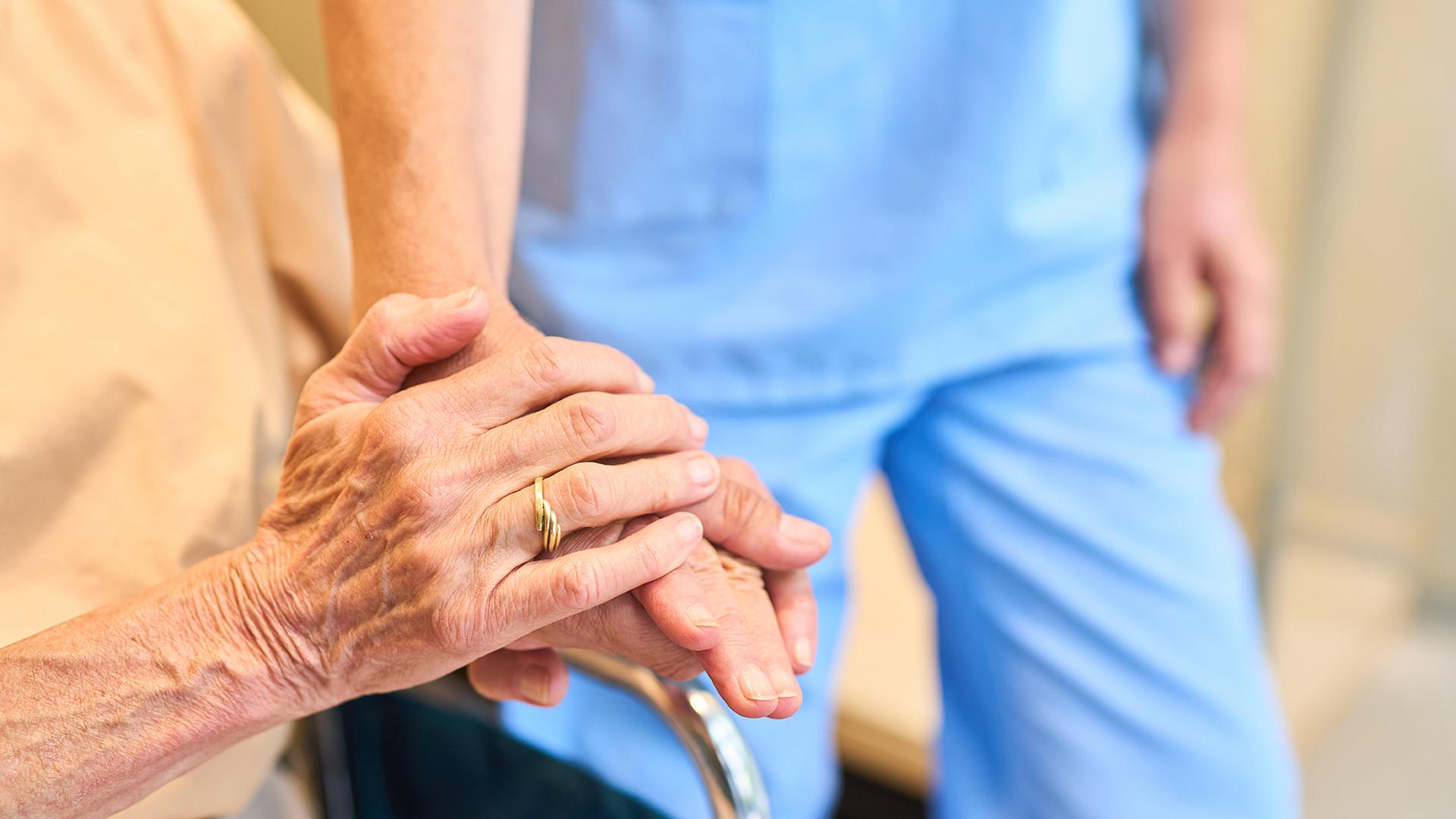 Eine ältere Person wird von einer Pflegekraft unterstützt. | picture alliance / Zoonar