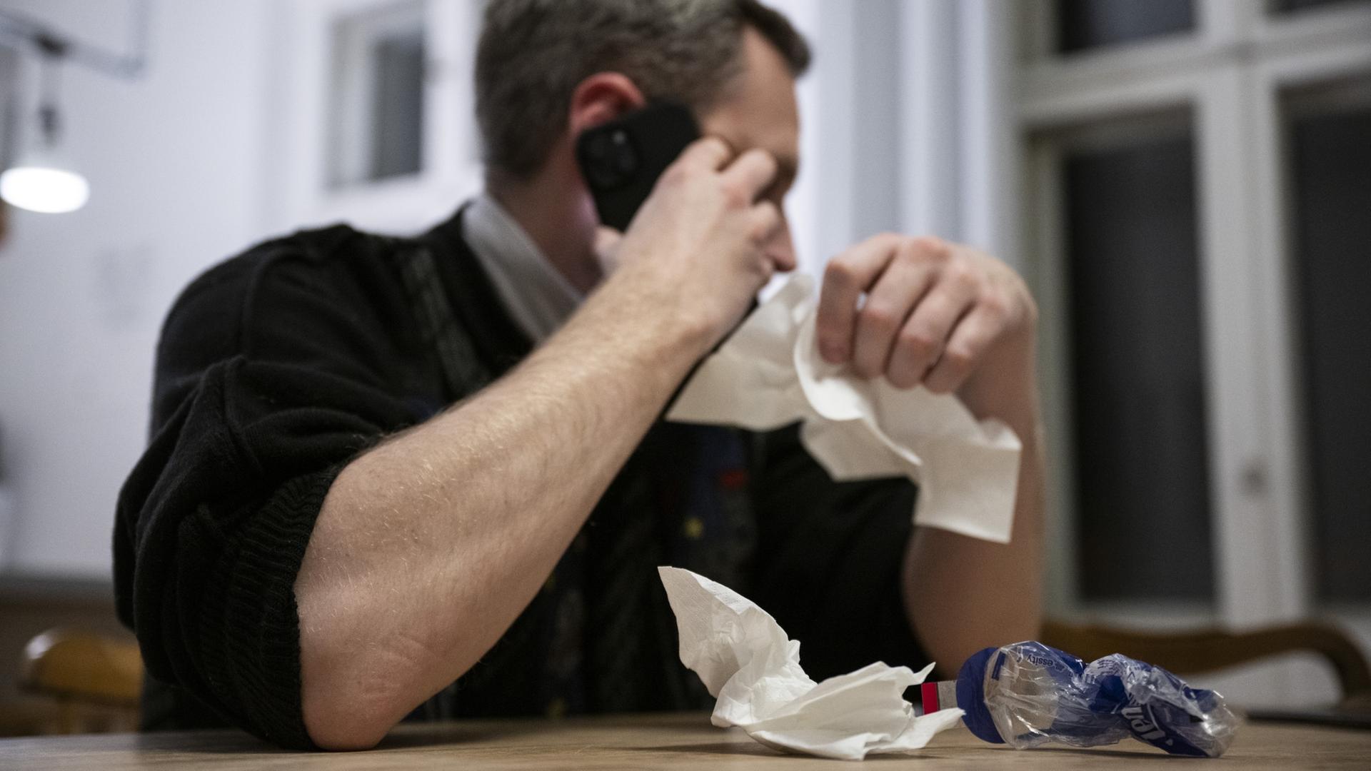 Ein Mann hält Taschentücher in der Hand und telefoniert. | dpa