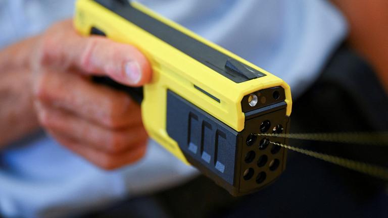 Ein Polizist hält eine Taser-Pistole.